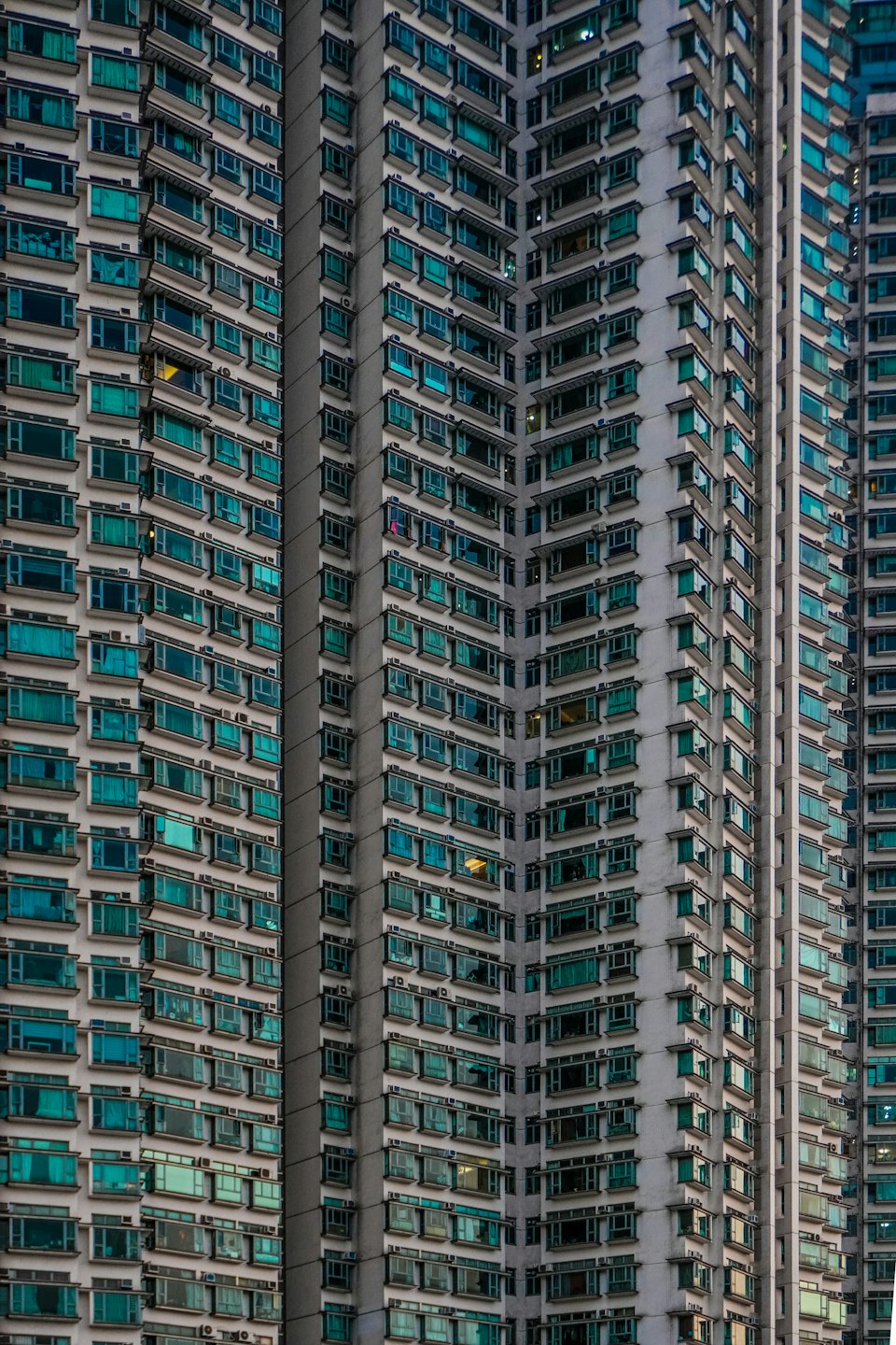 Modern apartment building facade with repeating teal windows.