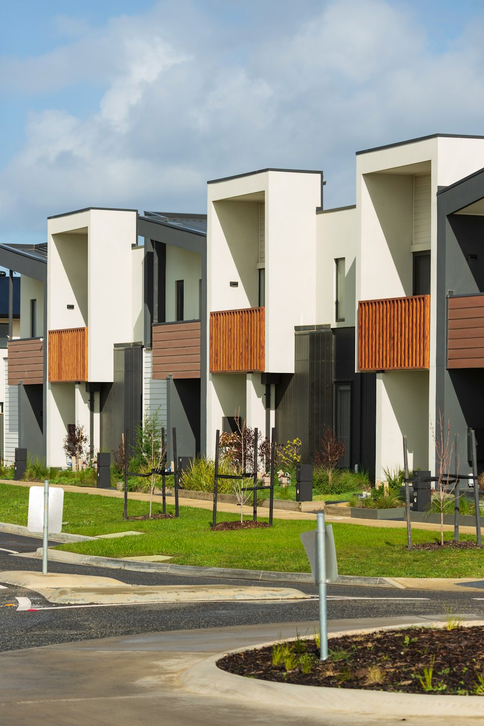 Modern townhouses with wooden accents line a new residential street.